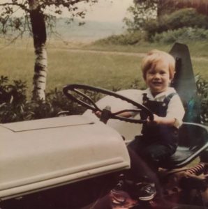 Childhood photo of Jeff Glor sitting on the tractor.