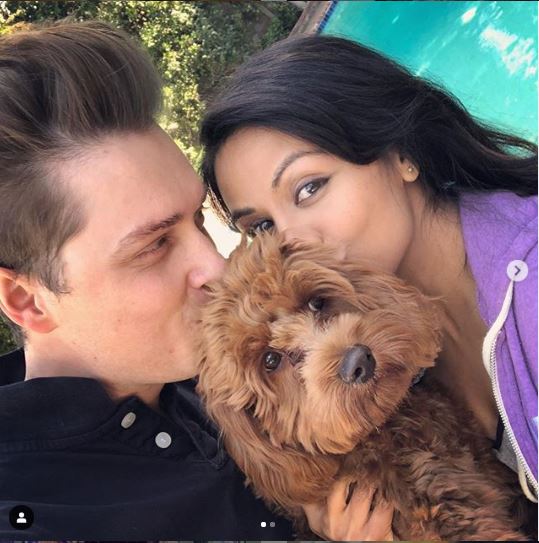 Karen David and her husband kissing their pet dog.