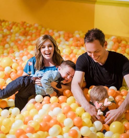 Jen Lilley with her husband playing with their children with lots of balloons.