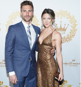 Andrew Walker wearing blue suit with his wife Cassandra wearing golden dress